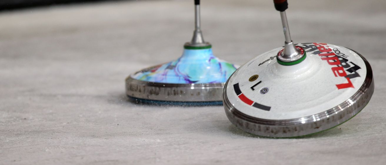 Zwei Spinner-Spielzeuge mit blauen und roten Griffen liegen auf einer weißen Oberfläche. Der linke hat ein blaues und weißes Wirbelmuster. Der rechte hat rote, weiße und grüne Details.
