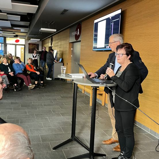 Bild enthält, Desk, Furniture, Table, Crowd, Person, Microphone, Glasses, Shoe, Adult, Man