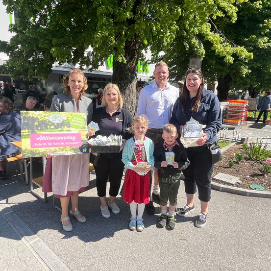 Fünf Personen stehen vor einem Baum. Sie halten eine Schachtel, ein Banner und ein Schild mit der Aufschrift Aktionssonnatag.