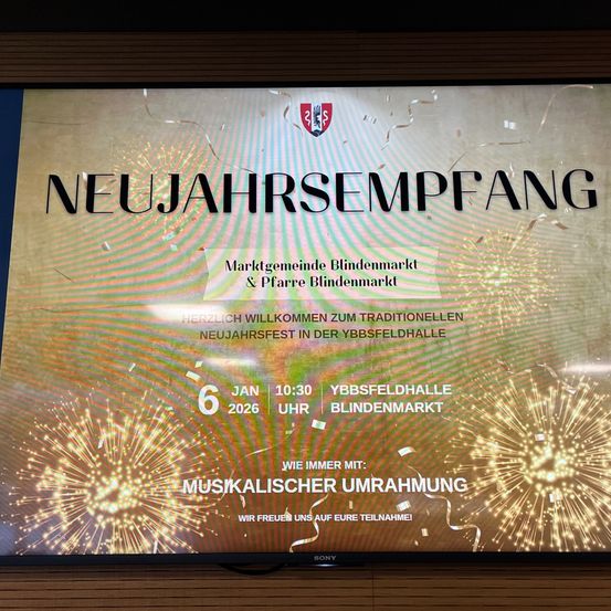 Ein Sony Fernseher zeigt eine Einladung zur Neujahrsfeier. Es steht 'Neujahrsempfang' mit Feuerwerk im Hintergrund. Die Veranstaltung wird von der Marktgemeinde und Pfarre Blindenmarkt ausgerichtet und findet am 6. Januar 2026 um 10:30 Uhr in der Ybbsfeldhalle Blindenmarkt statt. Musikalische Unterhaltung ist versprochen.
