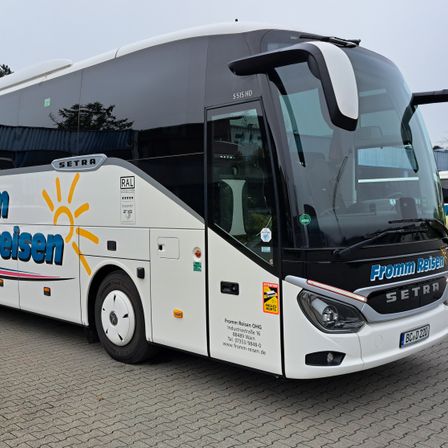 Ein weißer und schwarzer Luxusbus mit dem Wort Setra an der Seite und dem Wort Reisen vorne.