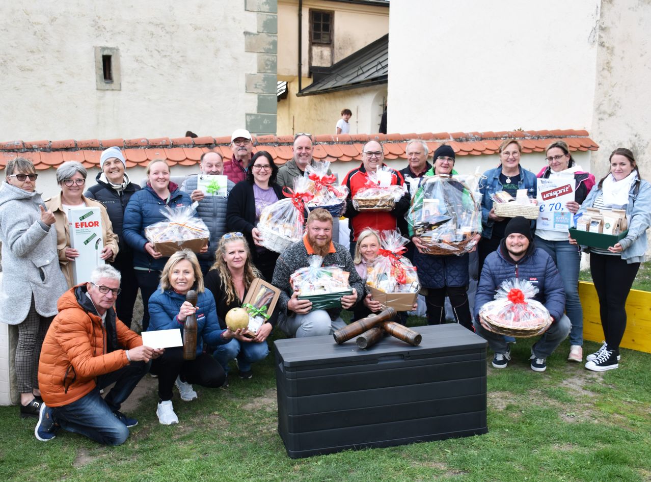 A group of people in winter clothing posing for a photo with gift baskets in front of a building.