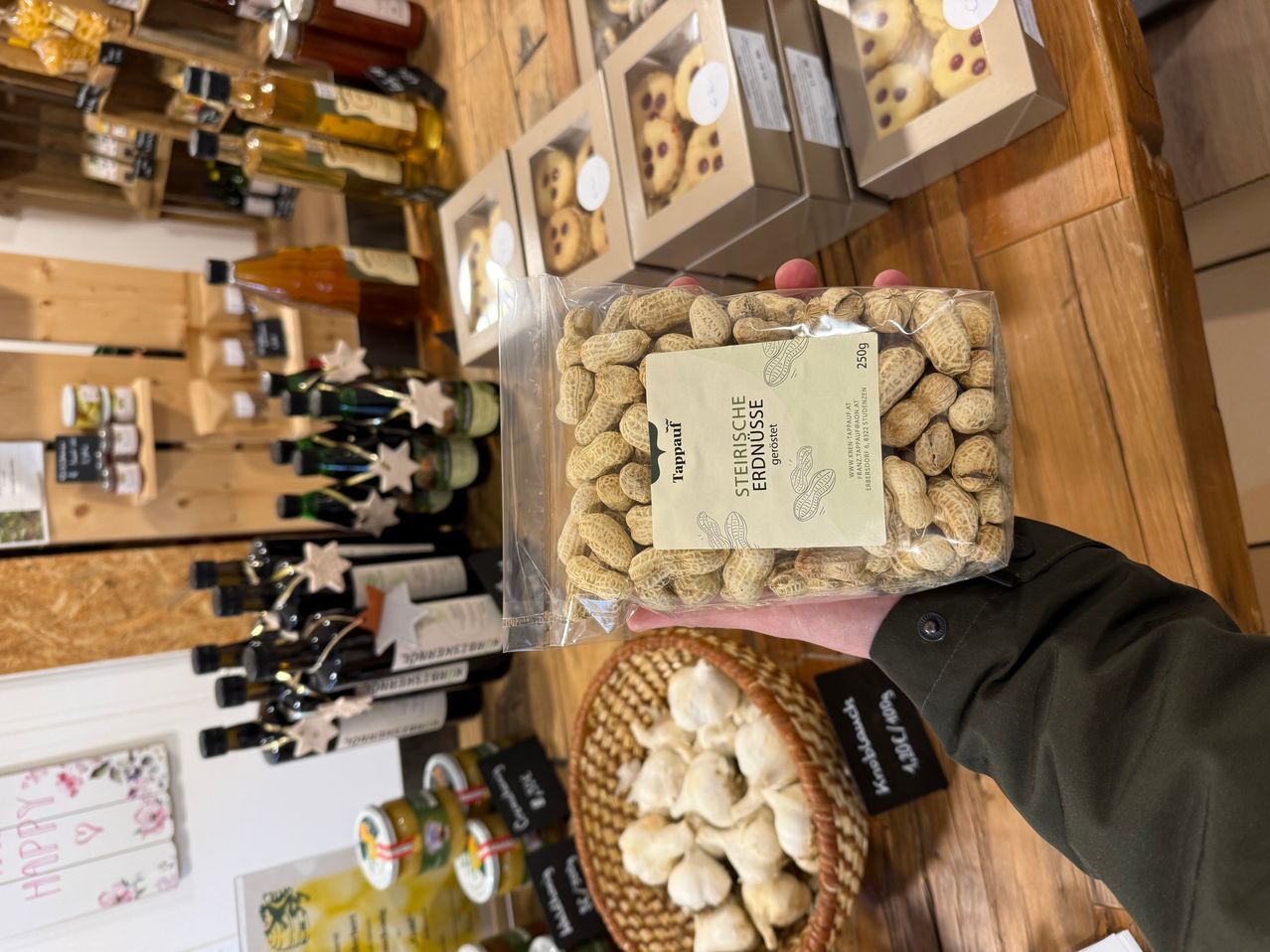 Eine Person hält eine Plastiktüte mit gerösteten Erdnüssen, mit anderen Lebensmitteln wie Flaschen und Schachteln im Hintergrund.