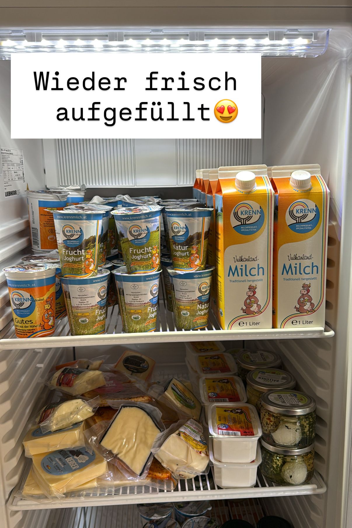 Ein Kühlschrank ist mit verschiedenen Milchprodukten gefüllt. Es gibt Joghurts, Milchkartons und Käse in Plastikbehältern. Die Joghurts haben das Label 'Krenn'. Zwei Milchkartons sagen 'Milch'. Der Textüberlagerung steht 'aufgefüllt'.