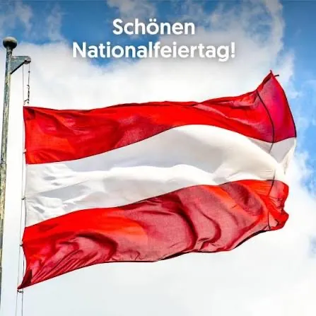 Eine rot-weiße Flagge mit einem weißen Streifen in der Mitte weht im Wind. Die Flagge ist an einem Mast befestigt, auf dem der Text 'Schönen Nationalfeiertag!' steht.