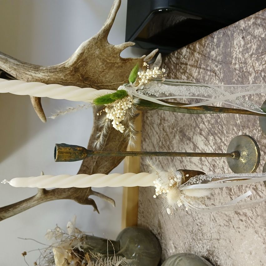 Zwei große Spiralkerzen sind auf einer Marmoroberfläche platziert, verziert mit Blumen und Geweihen.