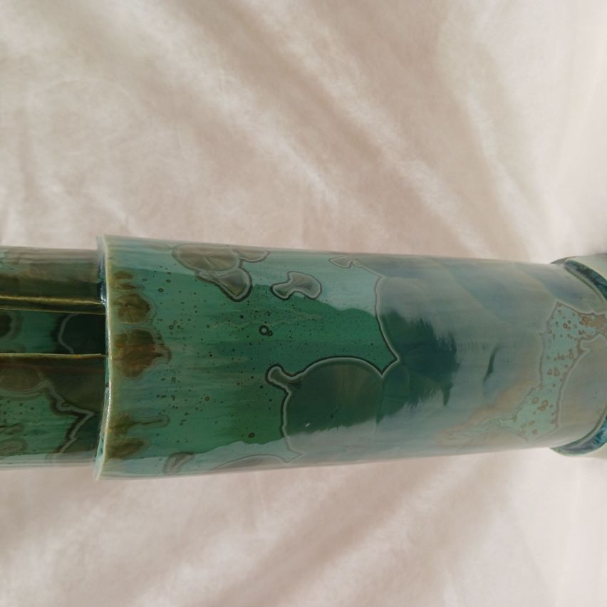 Eine Nahaufnahme eines zylindrischen Objekts mit einer strukturierten, grünen Oberfläche. Das Objekt zeigt ein wirbelndes Design mit dunkleren grünen Flecken.