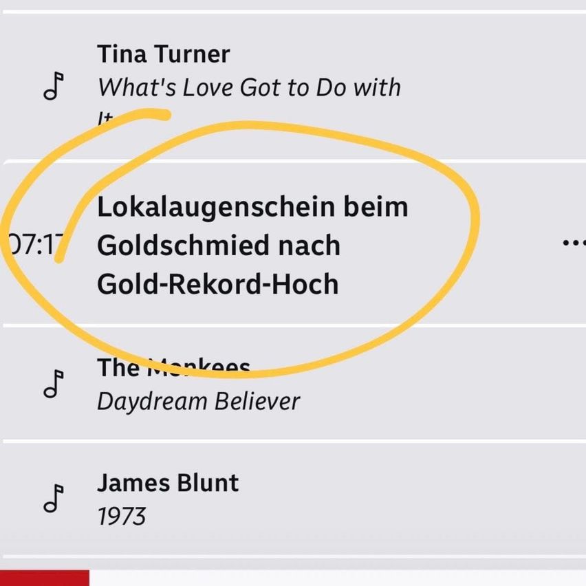 Ein Screenshot einer Musik-App zeigt eine Liste von Liedern. Oben steht Tina Turners 'What's Love Got to Do with It' mit einem Abspiel-Button-Symbol. Unten ist 'Lokalaugenschein' mit einem gelben Kreis hervorgehoben. Andere Songs sind The Monkees' 'Daydream Believer' und James Blunts '1973'.