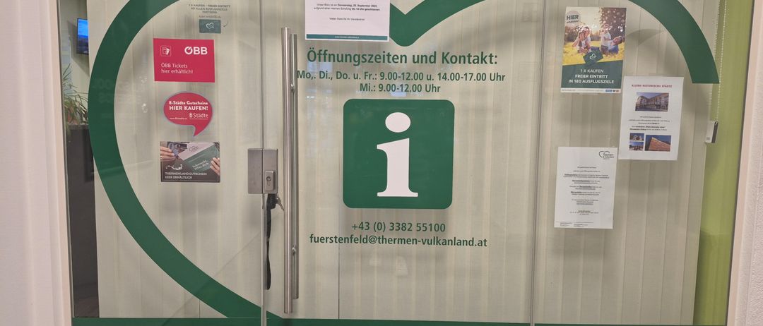 Eine Glastür zeigt 'Obb Bahnhof in der City' mit Öffnungszeiten Mo-Fr 9:00-12:00 und 14:00-17:00, Sa 9:00-12:00. Kontaktdaten sind aufgeführt mit Telefonnummer und E-Mail. Ein Schild sagt 'Gastinformation Furstenfeld' mit einer Website.