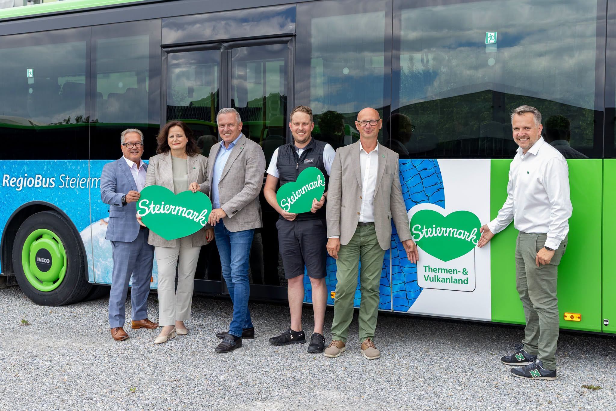 Steiermark: Fünf Personen halten Herzen mit dem Aufdruck „Steiermark“ vor einem RegioBus