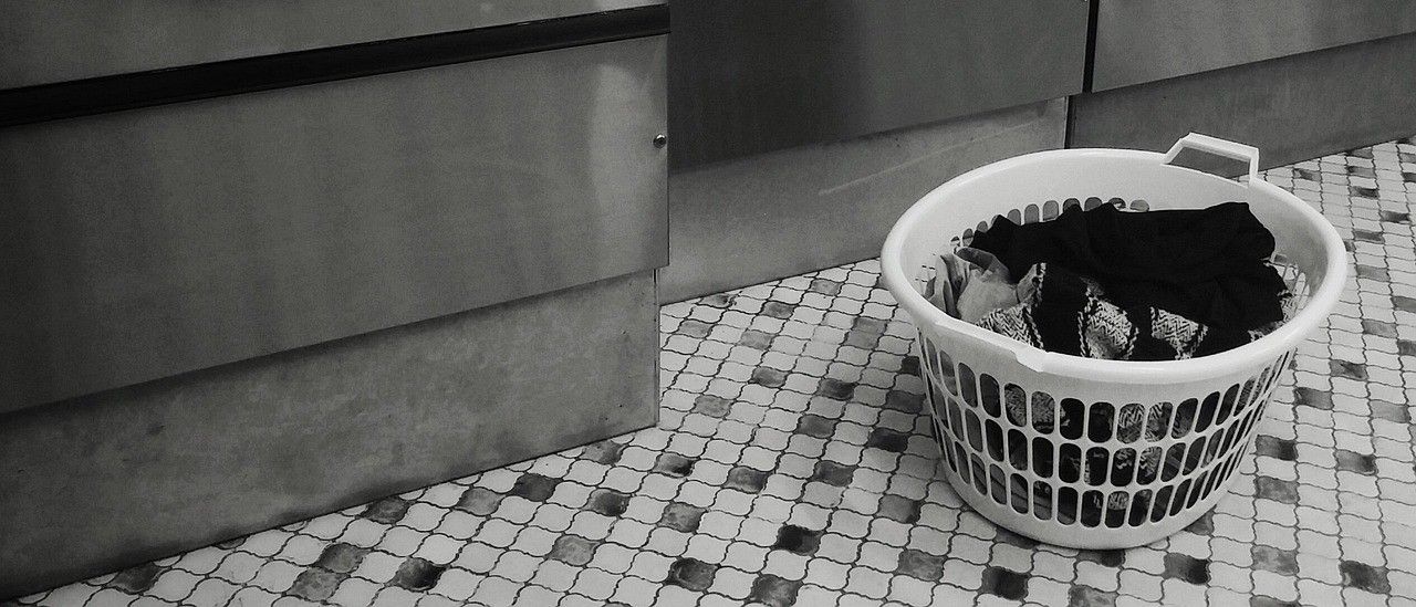 Ein Schwarz-Weiß-Foto einer Reihe von Waschmaschinen mit einem Korb voller Wäsche davor.