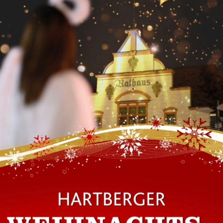 Eine Frau in einem weißen Kostüm steht vor dem Rathaus. Das Gebäude ist mit Schneeflocken und Sternen geschmückt, und der Himmel ist dunkel.