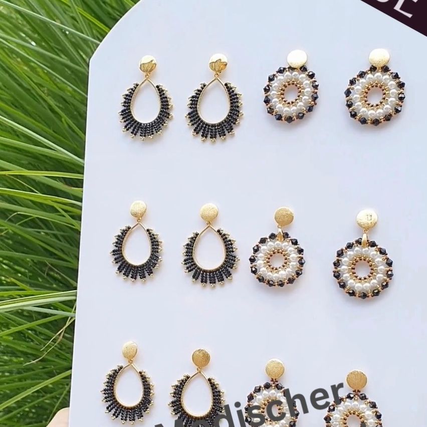 Eine Sammlung von goldenen und schwarzen Perlenohrringen, die auf einem weißen Hintergrund präsentiert werden. Jeder Ohrring hat ein einzigartiges Design mit schwarzen und weißen Perlen.