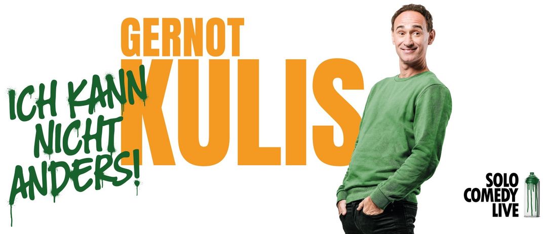 Ein Mann steht vor einem großen orangefarbenen Text, der 'Gernot Kulis' lautet. Er trägt ein grünes Shirt und schwarze Hose.