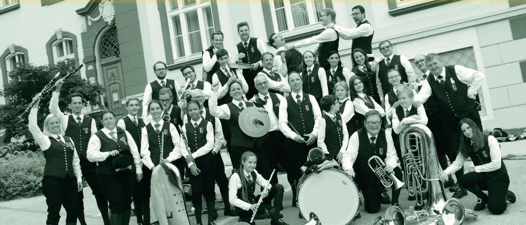 Eine Gruppe von Musikern posiert vor einem Gebäude für ein Foto und hält verschiedene Instrumente in den Händen. Der Text lautet 'Konzert', 'Sa. 25. April 2026' und 'Kunsthaus Weiz'. Die Veranstaltung beginnt um 19:00 Uhr.