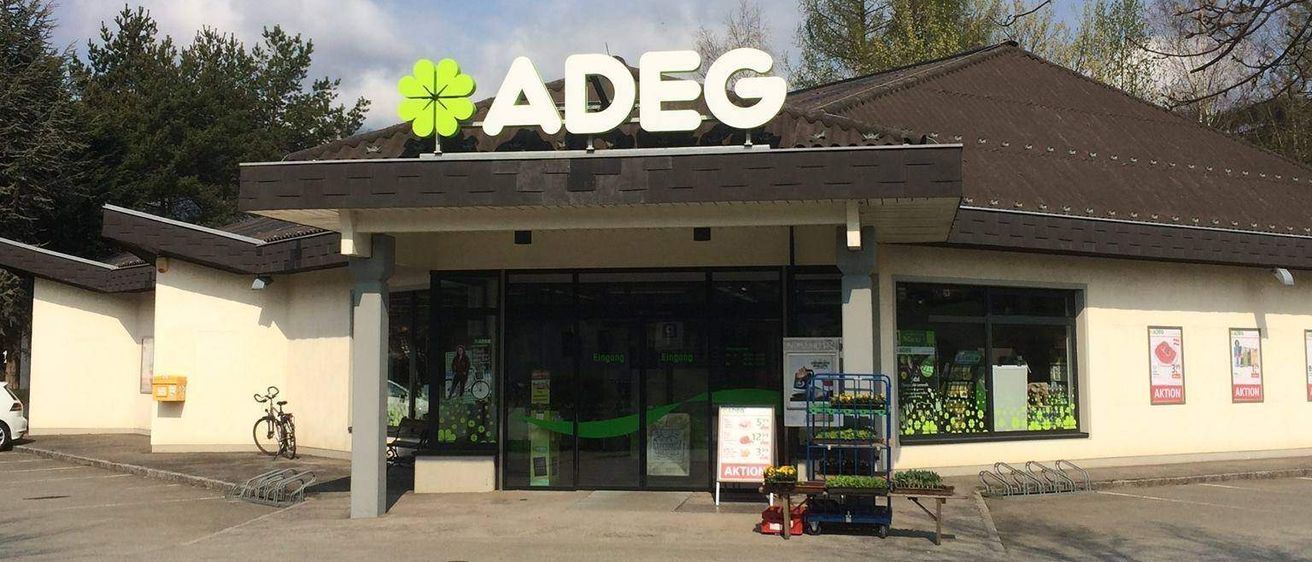 Adeg-Geschäft mit Parkplatz davor. Ein Fahrrad ist draußen geparkt.