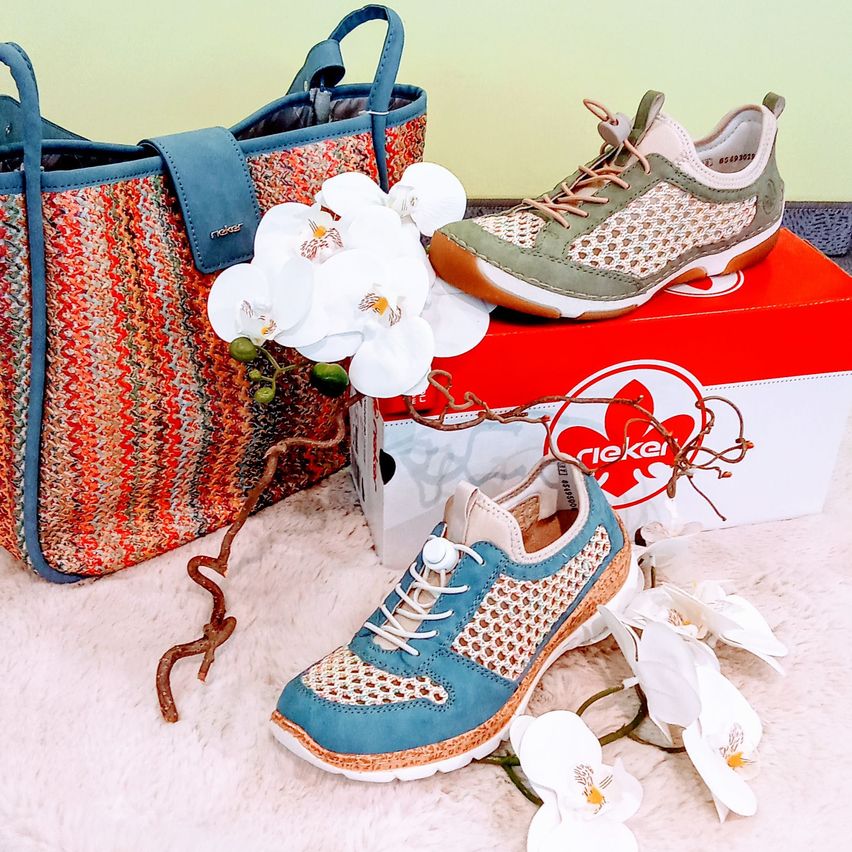 Ein blauer und weißer Sneaker mit einer roten Box, einer gewebten Tasche und weißen Blumen auf einer weißen Oberfläche.