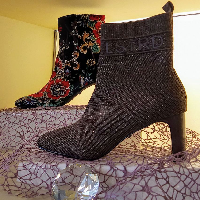 Zwei Stiefelpaare ausgestellt, eines mit Blumenmustern und das andere mit einem Markenlogo.