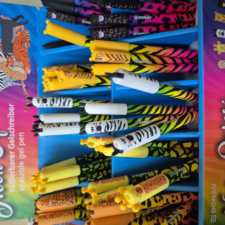 Eine Auswahl an bunten und tierförmigen Gelstiften in einem blauen Display. Designs beinhalten Zebras, Tiger und Giraffen mit Radiergummis. Die Markenbezeichnung lautet 'DONAU'.