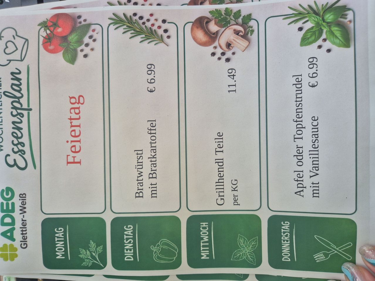 Ein Menü, das die Preise für verschiedene Wochentage zeigt. Montag hat Bratwurst mit Bratkartoffeln für 6,99 Euro. Dienstag hat gegrilltes Hähnchen pro Kilogramm für 11,49 Euro. Mittwoch hat Apfel oder Toppingstrudel für 6,99 Euro.