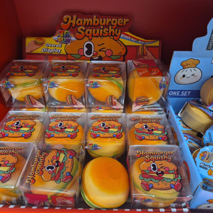 A display of colorful Hamburger Squishy toys in clear plastic packaging, arranged in rows with a sign that reads Hamburger Squishy Overall Display.