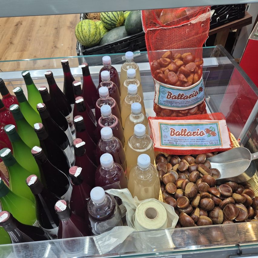 Eine Glasvitrine mit verschiedenen Flaschen Wein, Saftflaschen und Tüten mit Kastanien.
