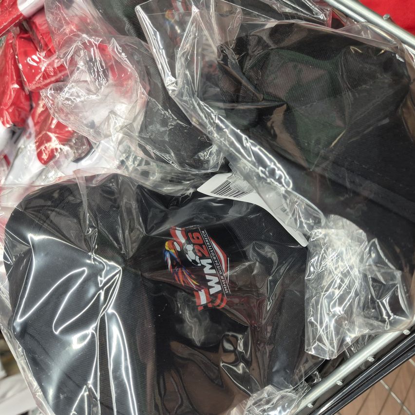Various black caps in clear plastic bags on a trolley, one with a logo reading MMA 26 TECH.