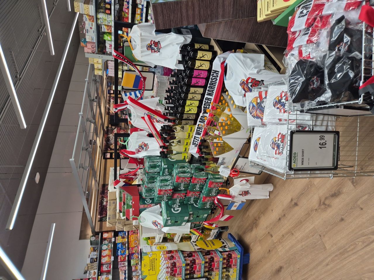 A grocery store with various products displayed. Many items are stacked and some are in plastic bags. The floor is wooden.