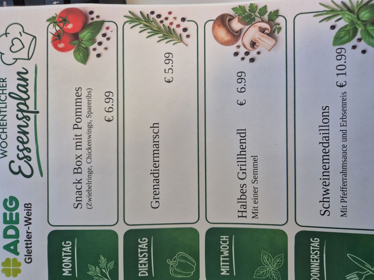 Ein Menü mit vier Optionen: Snack Box mit Pommes, Grenadiermarsch, Halbes Grillhendl, und Schweinemedaillons. Jeder Artikel hat einen Preis und die Tage der Verfügbarkeit.