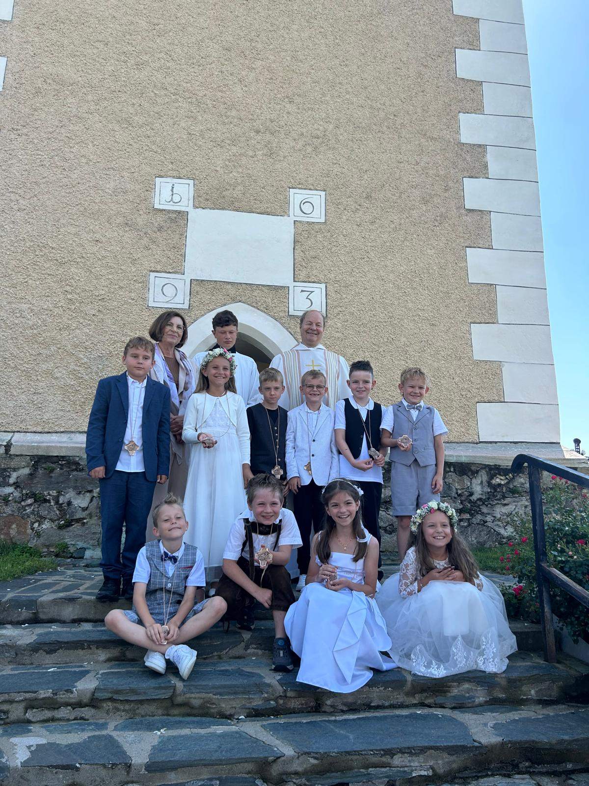 Kommunionkinder und Geistlicher vor Kirche in Österreich