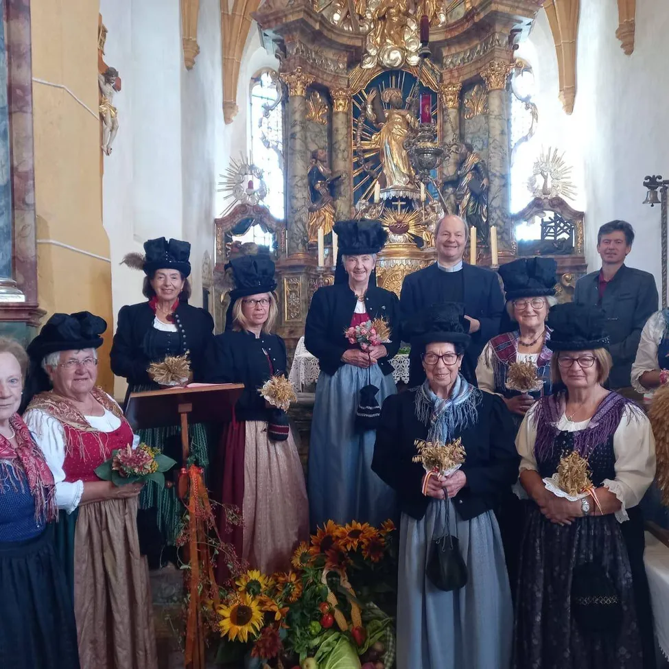 Eine Gruppe von Frauen und Männern in traditioneller Kleidung posiert für ein Foto in einer Kirche.