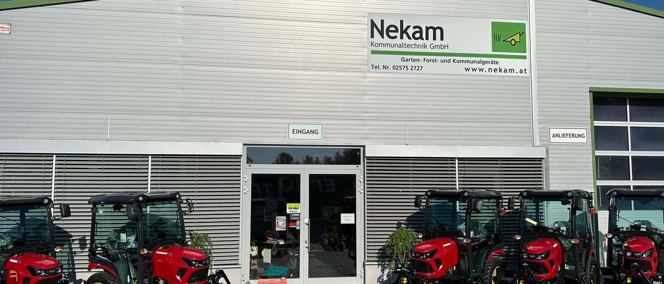 Die Vorderseite der Firma Nekam Kommunaltechnik GmbH, die Garten-, Forst- und Kommunalgeräte verkauft. Zwei rote Traktoren sind davor geparkt.