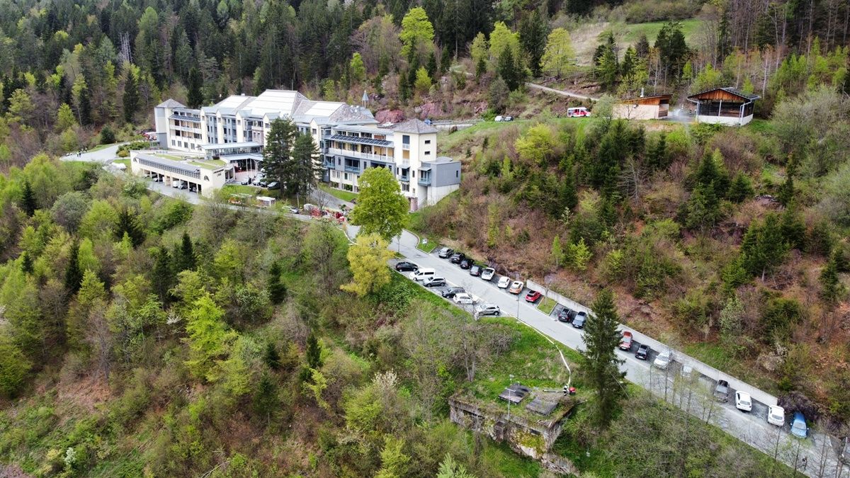 Luftaufnahme eines Hotelkomplexes mit zahlreichen Autos, die in einem von üppiger Grün umgebenen Parkplatz geparkt sind.