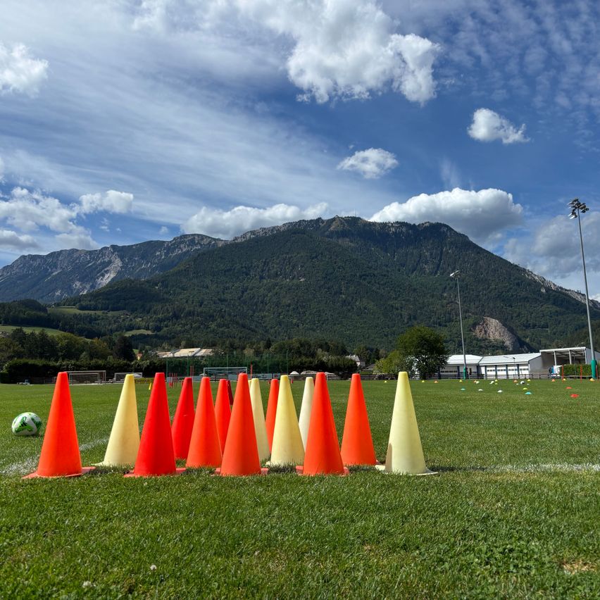 Fußballplatz mit Trainingskegeln und Bergkulisse in Tirol
