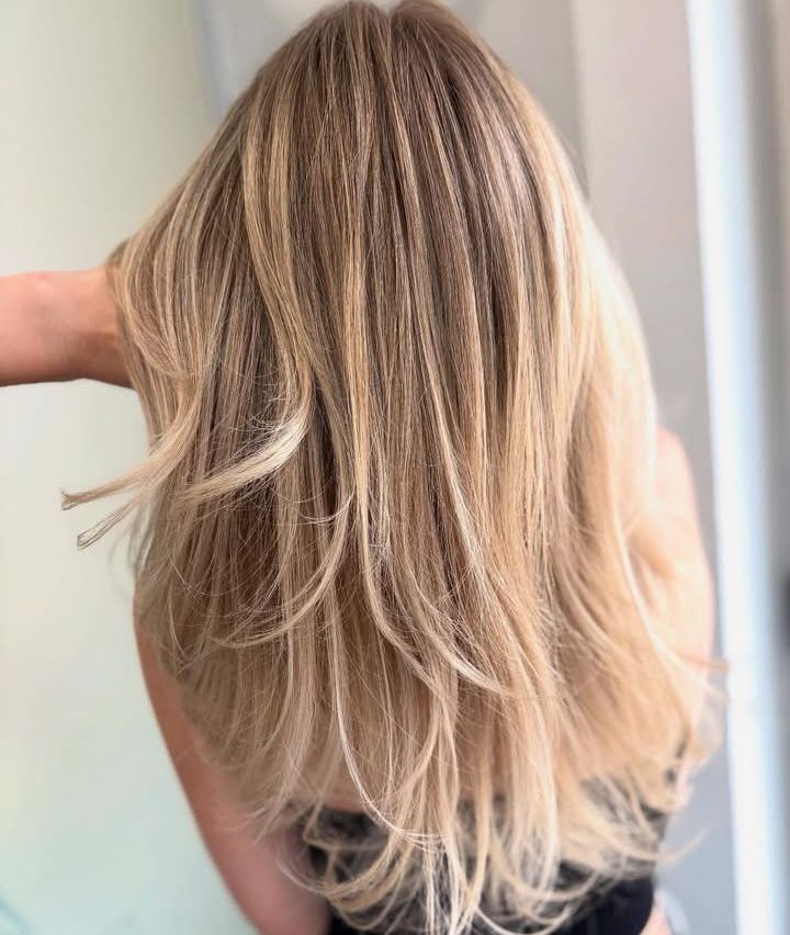 Eine Frau mit langen, blonden Haaren hält ihr Haar und bereitet sich möglicherweise auf ein Fotoshooting vor.