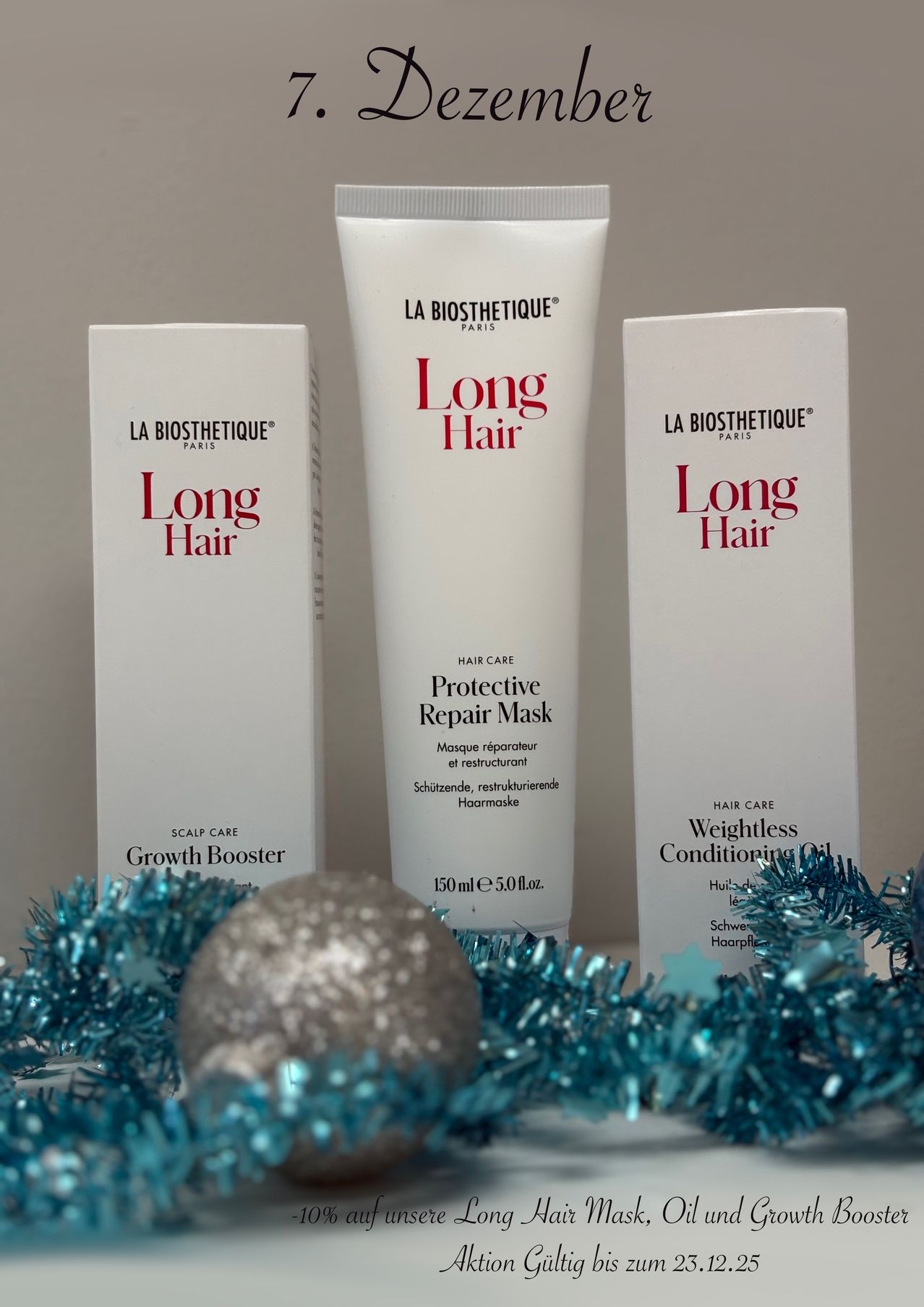 Drei La Biosthetique Haarpflegeprodukte ausgestellt: Wachstumsstimulator, Schützende Reparaturmaske und Gewichtloses Pflegeöl. Die Artikel sind auf einem Hintergrund aus blauer Tinsel platziert.