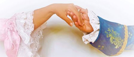 Zwei Hände, die sich halten, mit einem weißen Spitzentuch und einem Ring am Mittelfinger der linken Hand.