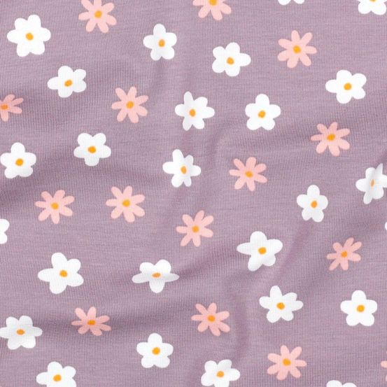 Eine Nahaufnahme eines weichen Stoffes mit einem Muster aus weißen und rosa Daisys auf einem lila Hintergrund. Die Blumen haben ein gelbes Zentrum und sind in einem verstreuten Muster angeordnet.