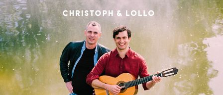 Zwei Männer stehen im Fluss und lächeln. Einer spielt Gitarre, der andere steht hinter ihm. Das Wasser reflektiert sie und die umliegenden grünen Bäume. Oben steht Christoph & Lollo, darunter alles gut.