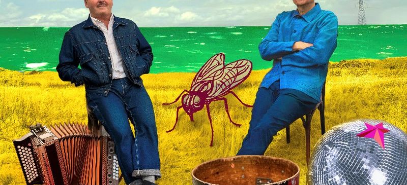 Zwei Männer sitzen auf einem gelben Feld mit Musikinstrumenten um sie herum. Einer hat ein Akkordeon und der andere einen Trommel. Ein rotes Moskito und eine Discokugel sind in der Nähe.
