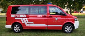 Ein roter Feuerwehrwagen mit MTFA und Johnsdorf-Brunn an der Seite steht auf dem Rasen.