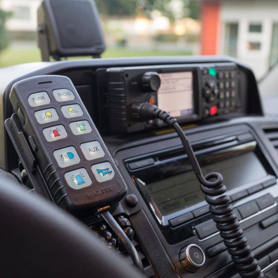 Ein Nahaufnahme des Armaturenbretts eines Fahrzeugs mit einem schwarzen Radio, einem schwarzen Kabel und einer Fernbedienung mit verschiedenen Tasten.