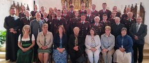 Eine Gruppe von Menschen in Uniform, möglicherweise ein Chor, posiert für ein Foto vor einem Altar in einer Kirche.