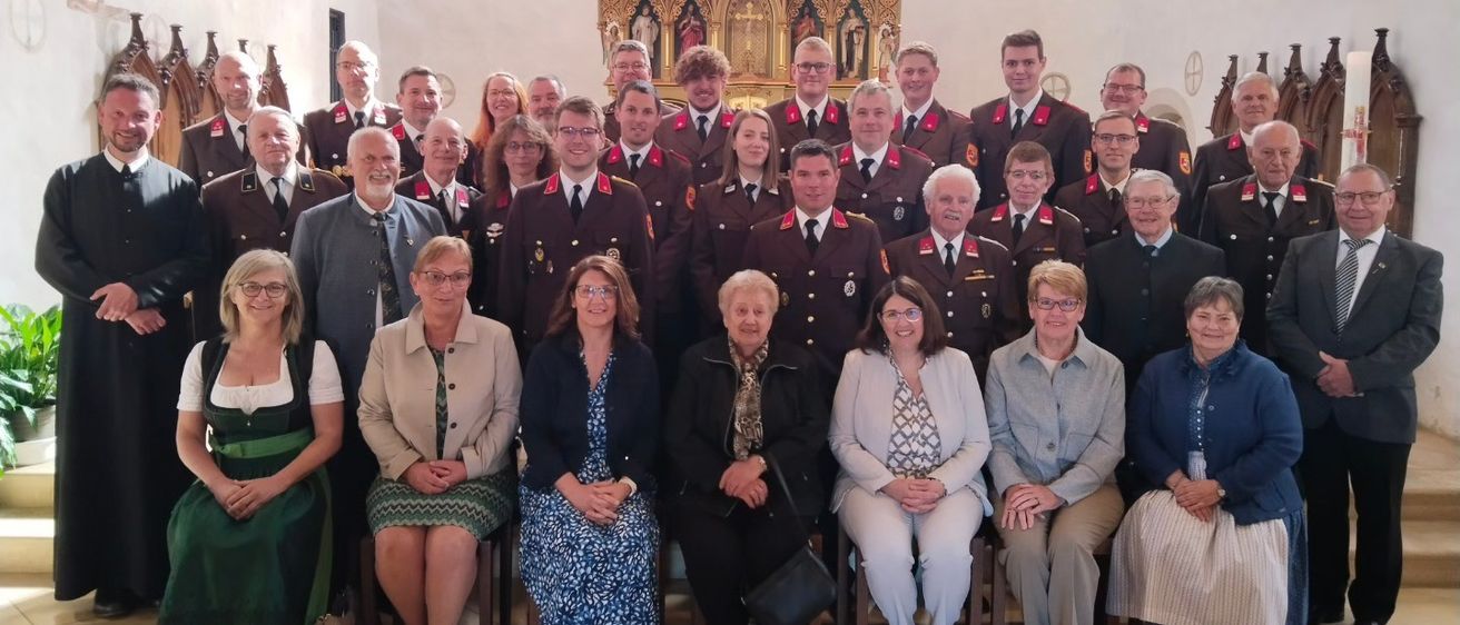 Eine Gruppe von Menschen in Uniform, möglicherweise ein Chor, posiert für ein Foto vor einem Altar in einer Kirche.