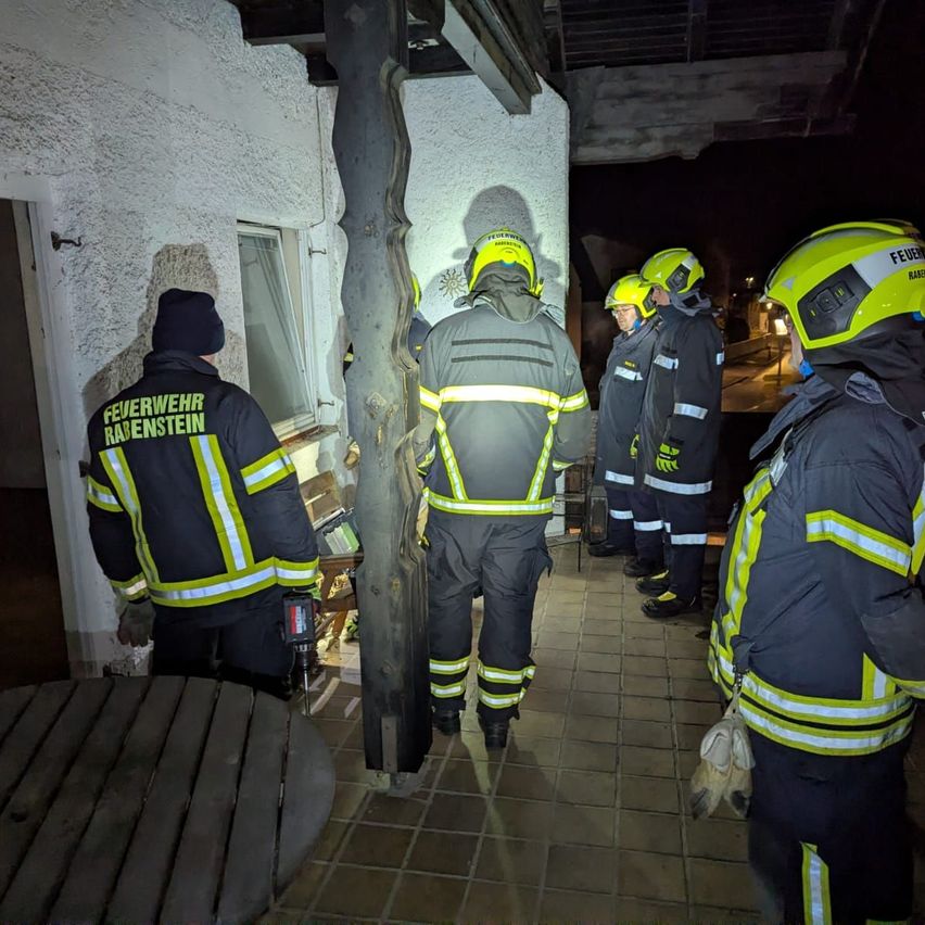 Eine Gruppe von Feuerwehrleuten in Schutzkleidung steht nachts vor einem Gebäude. Sie bereiten sich möglicherweise auf einen Notfall vor.