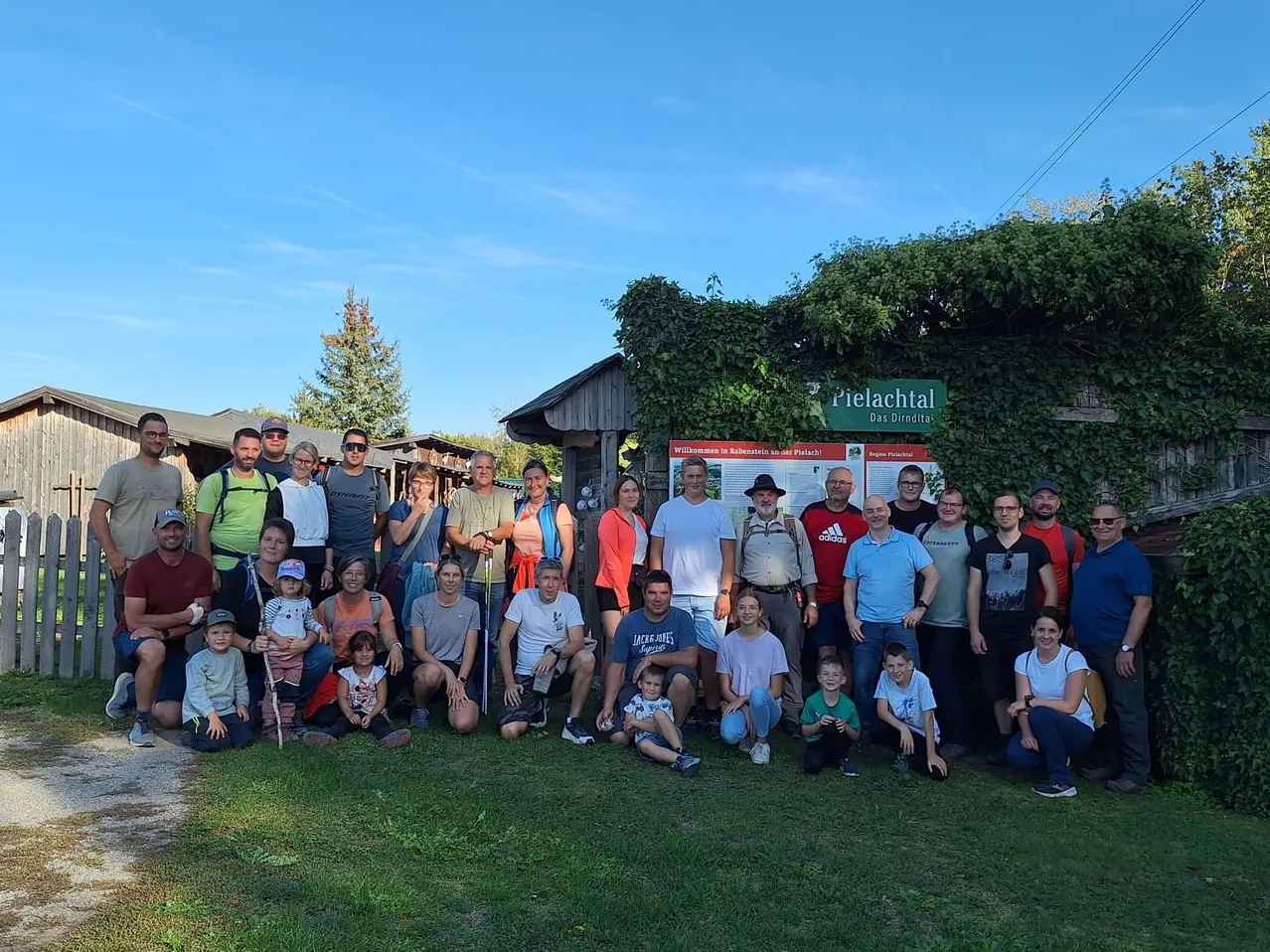 Eine Gruppe von Menschen posiert für ein Foto vor einem Haus mit einem Schild, das 'Pielachertal' steht.