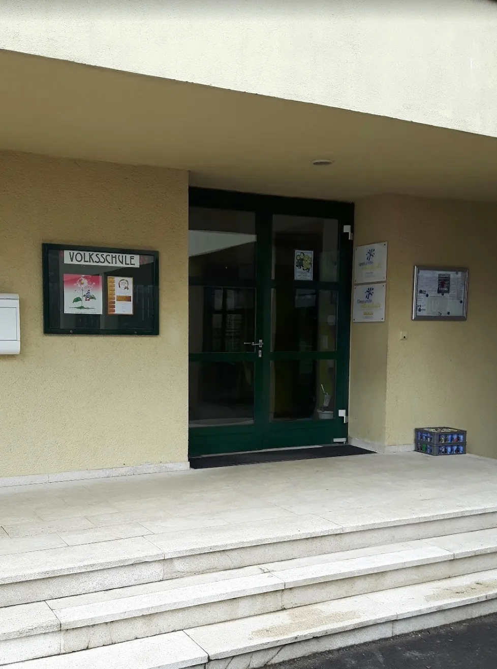 Der Eingang zu einem Gebäude mit einem Schild, das 'Volksschule' besagt.