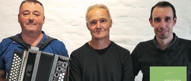 Drei Männer posieren für ein Foto, einer hält ein Akkordeon, der andere ein Buch. Datum und Uhrzeit unten angegeben. Wolfgang Kühn und Herbert Eigner-Kobenz. Veranstaltung mit dem Titel 'Pongen im Dialekt'.