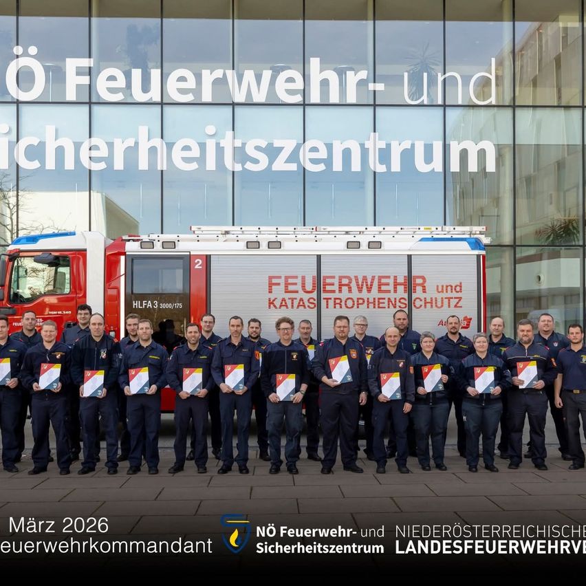Eine Gruppe Feuerwehrleute in Uniform posiert im März 2026 vor einem Feuerwehrauto. Das Foto hat einen Wasserzeichen mit dem Text 'NO Feuerwehr- und Sicherheitszentrum Landesfeuerwehrverband'.