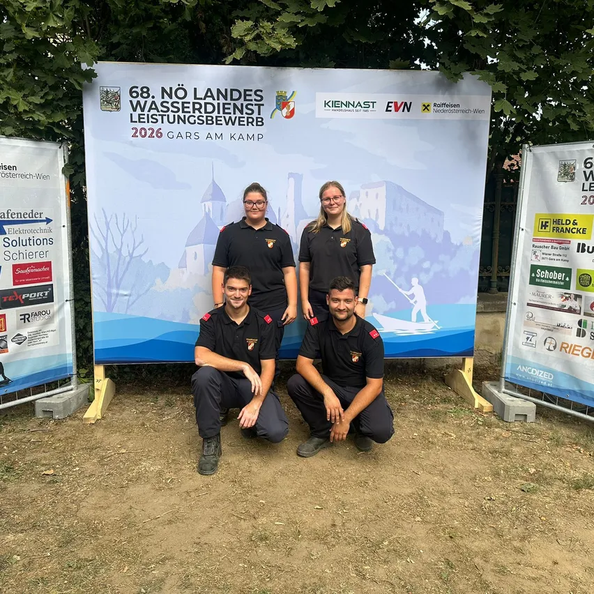 Vier Personen in Uniform posieren für ein Foto vor einem großen Banner, das die 68. Nationale Wasserdienstleistungswettbewerb im Jahr 2026 bewirbt.